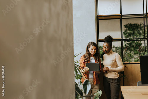 Two young business women with digital tablet standing in the modern office © BGStock72