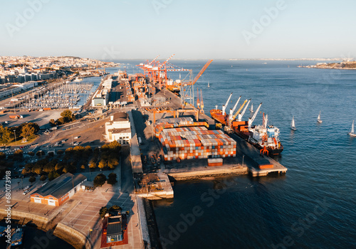 Aerial photo of scenic view of big cargo container ship loading Lisbon (Portugal) on sunset. Port harbour seaport cranes at warm sunset. Commercial trade freight from above - taken by drone.