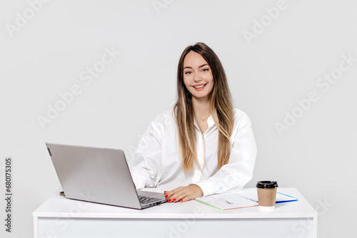 girl psychologist sitting at a table with a laptop smiling isolated on a white background photo