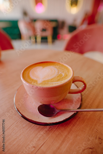 A cup of cappuccino on the table in a pink cafe