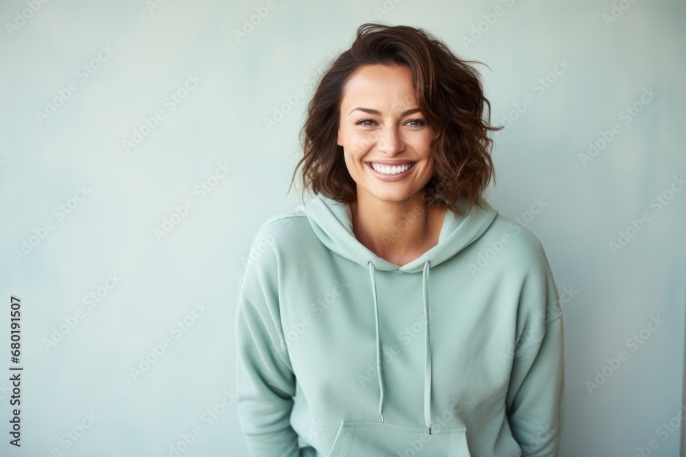 Portrait of a happy woman in her 30s sporting a comfortable hoodie against a pastel teal background. AI Generation Portrait of a happy woman in her 30s sporting a comfortable hoodie against a pastel teal background. AI Generation
