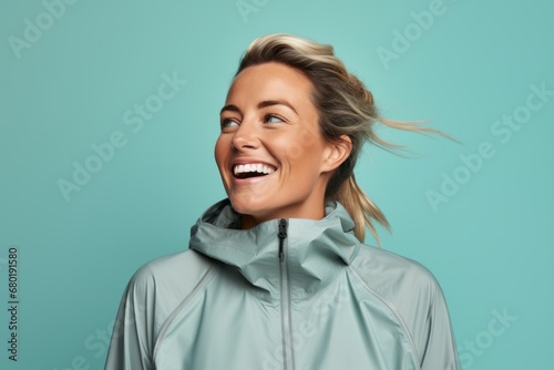 Portrait of a blissful woman in her 30s wearing a windproof softshell against a pastel teal background. AI Generation photo