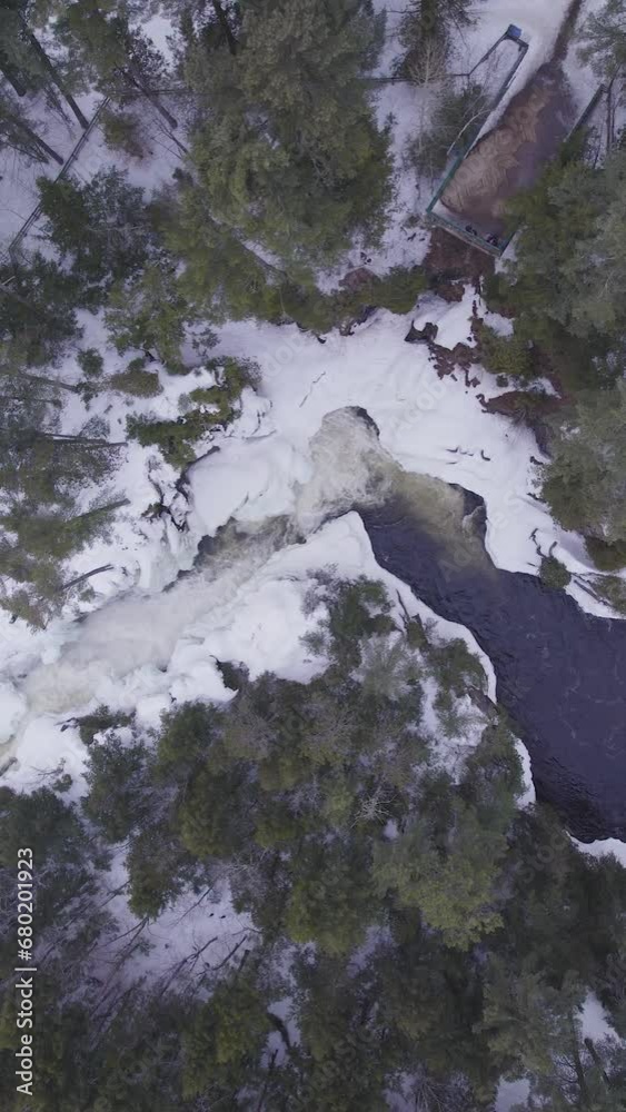 Aerial view of white winter landscape with a frozen river in the forest with flowing water in Laurentides Canada Aerial view of white winter landscape with a frozen river in the forest with flowing water in Laurentides Canada