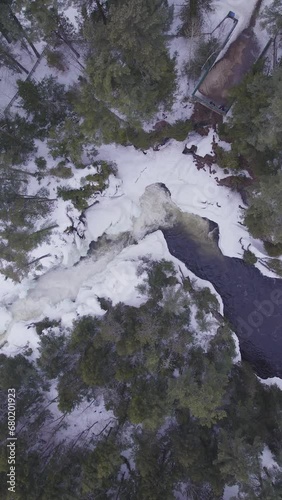 Aerial view of white winter landscape with a frozen river in the forest with  flowing water in Laurentides Canada (ID: 680201923)