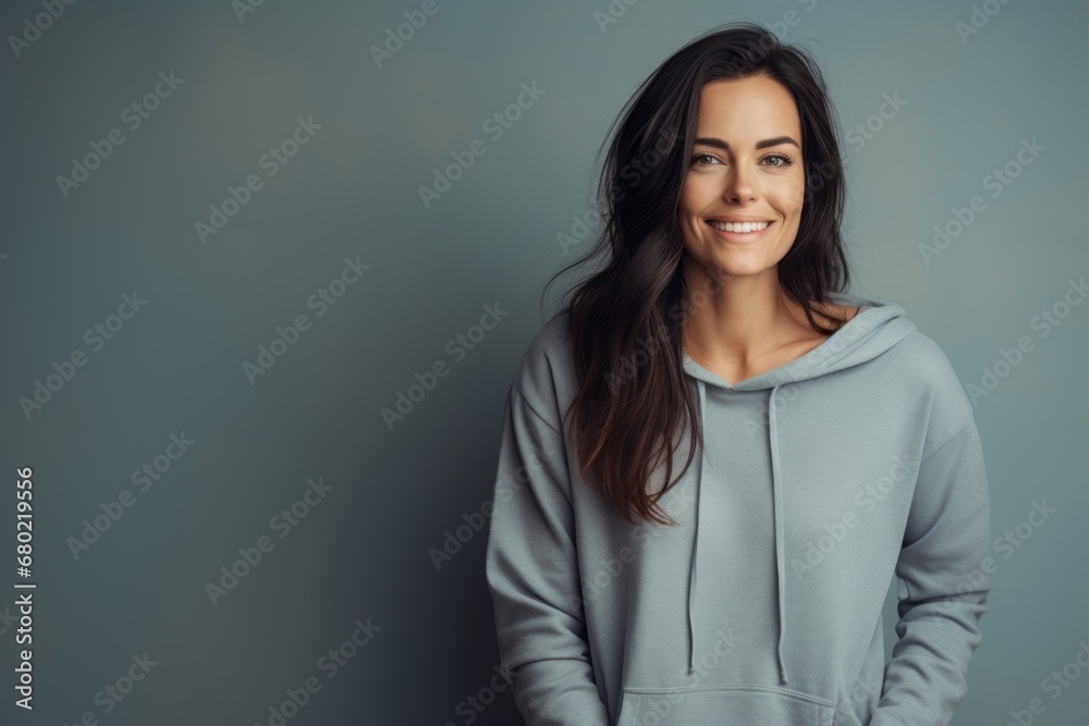 Fototapeta premium Portrait of a glad woman in her 30s sporting a comfortable hoodie against a minimalist or empty room background. AI Generation