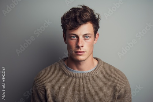 Portrait of a glad man in his 20s dressed in a warm wool sweater against a minimalist or empty room background. AI Generation