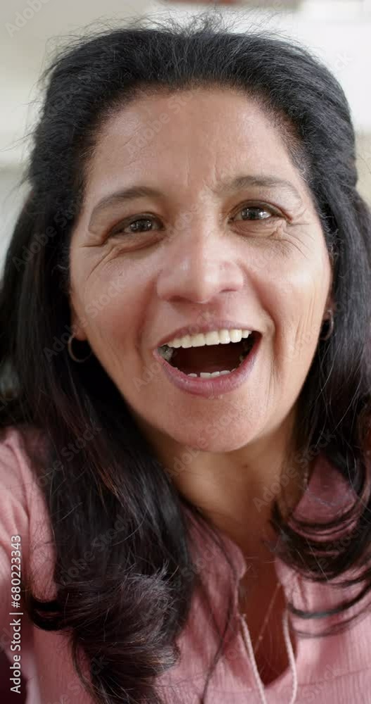 Happy biracial senior woman having video call and waving hand in sunny room, slow motion Happy biracial senior woman having video call and waving hand in sunny room, slow motion