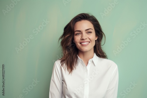 Portrait of a grinning woman in her 30s wearing a classic white shirt against a solid pastel color wall. AI Generation