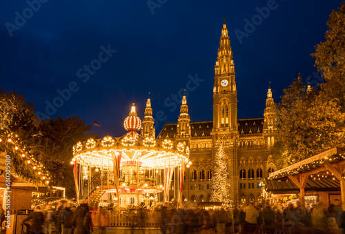 The carousel of the Christmas market in Rathaus park with City Hall in the center - Vienna, Austria