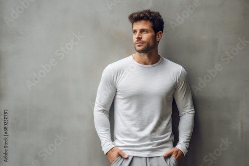 Portrait of a blissful man in his 30s showing off a lightweight base layer against a bare concrete or plaster wall. AI Generation