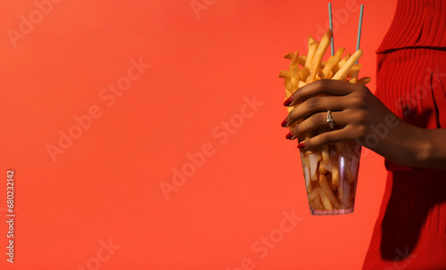 Mano sujetando patatas fritas. Mano con uñas largas y joyas. Color rojo. Fondo rojo. Aesthetic. Moda. Generado con IA. 