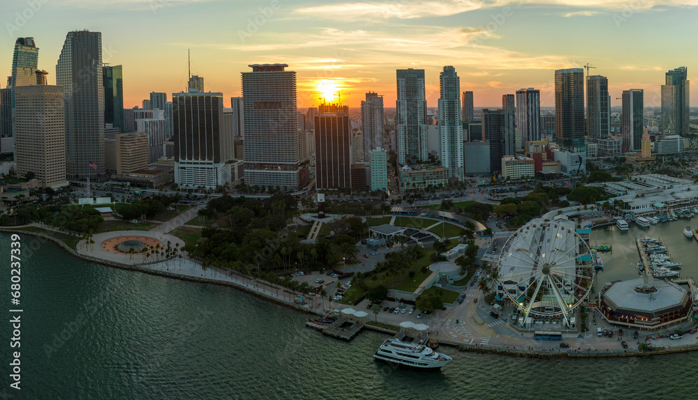 American urban landscape at sunset. Skyviews Miami Observation Wheel at Bayside Marketplace with reflections in Biscayne Bay water and high illuminated skyscrapers of Brickell, city's financial center