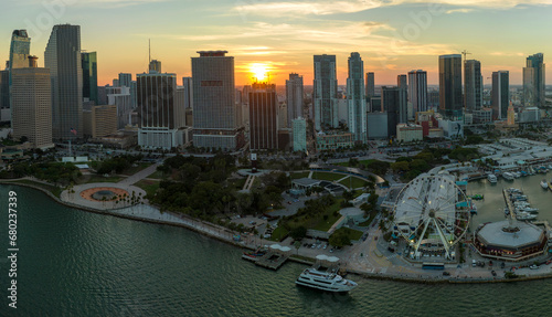 American urban landscape at sunset. Skyviews Miami Observation Wheel at Bayside Marketplace with reflections in Biscayne Bay water and high illuminated skyscrapers of Brickell  city s financial center