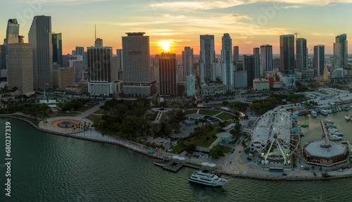 American urban landscape at sunset. Skyviews Miami Observation Wheel at Bayside Marketplace with reflections in Biscayne Bay water and high illuminated skyscrapers of Brickell, city's financial center