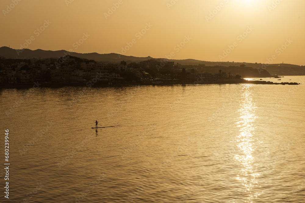 Fototapeta premium The man paddleboarding on sea early sunset