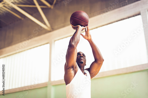 Young man shooting a basketball in an indoor basketball gym photo