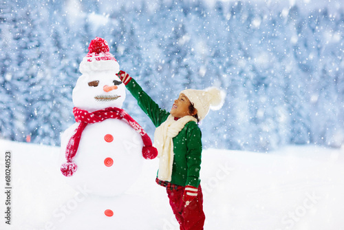 Child building snowman. Kids build snow man. © famveldman