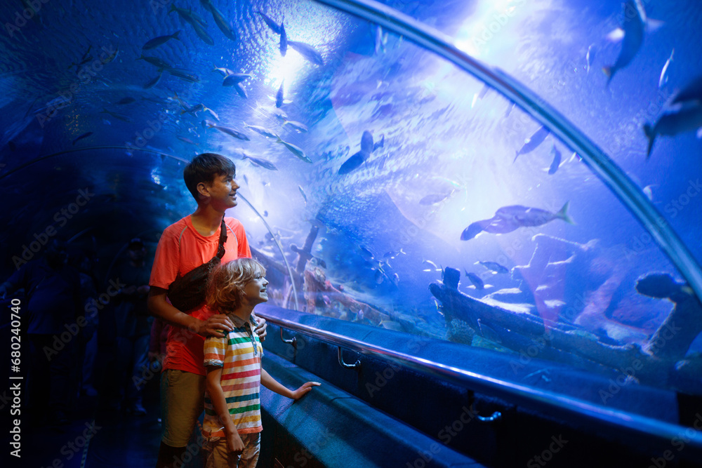 Naklejka premium Family in aquarium. Kids watch fish, marine life