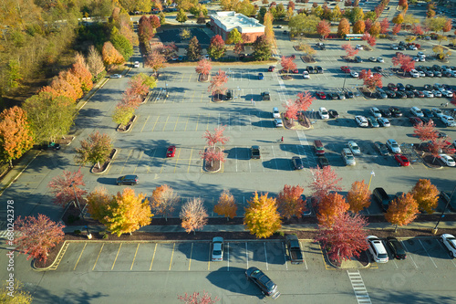 View from above of many parked cars on parking lot with lines and markings for parking places and directions. Place for vehicles in front of a strip mall center photo