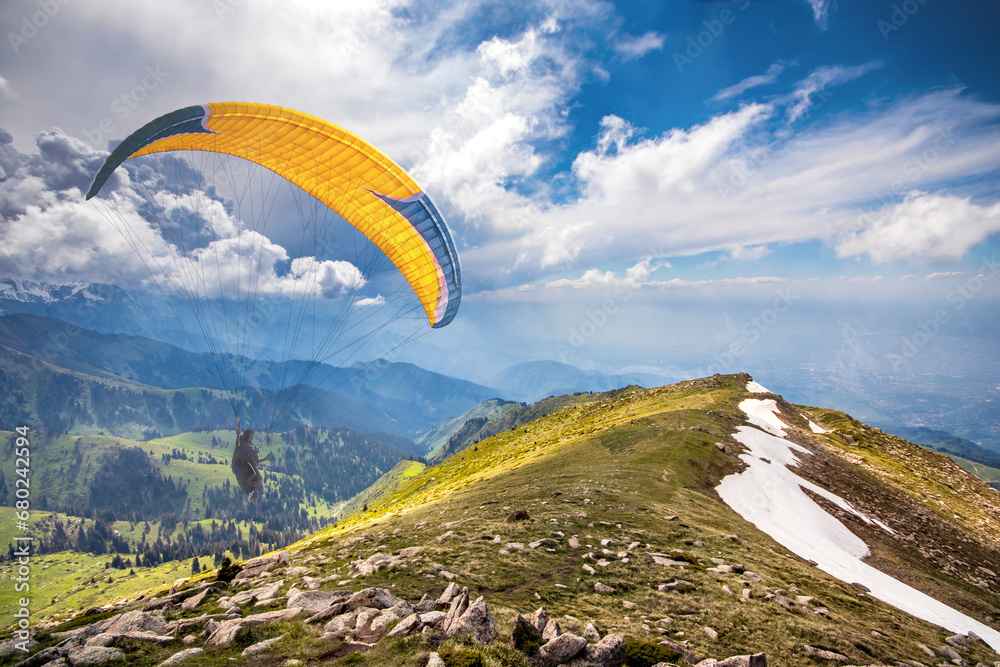 Paraglider is planning in the sky in a picturesque hilly area. Paraglider is planning in the sky in a picturesque hilly area.