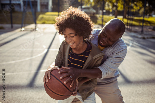 Father and Son Enjoying a Game of Basketball Outdoors photo