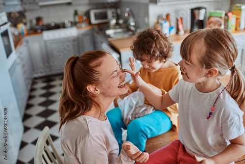 Bild auf Leinwand Mother and Children Playing with Food in the Kitchen