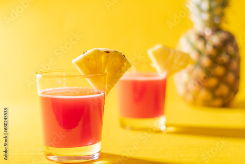 Pineapple juice in glass closeup near sliced fruit with spash and dripping liqid for summer vibes. photo