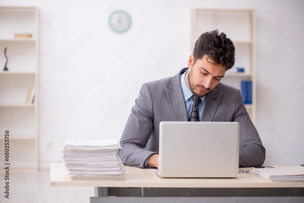 Young male employee and too much work in the office Young male employee and too much work in the office