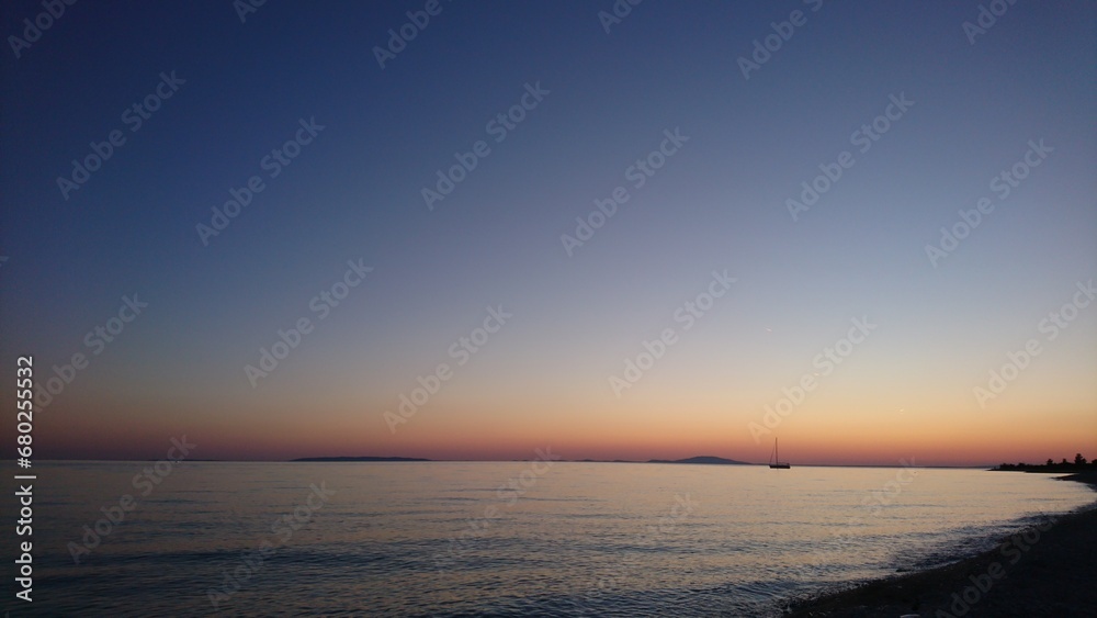 Fototapeta premium Boat in the distance and orange sunset in the evening