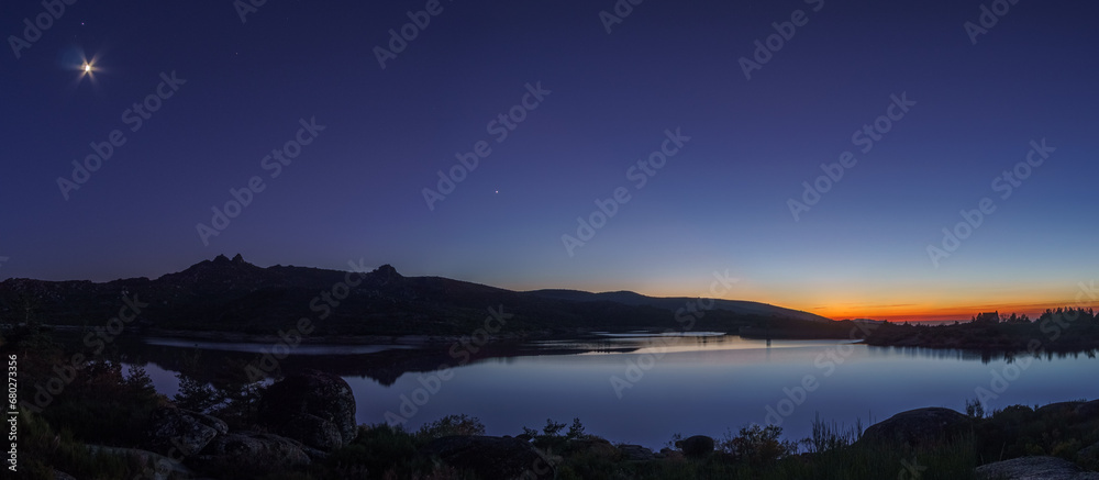 Panorama of colorful twilight with Crescent moon and planets Venus, Saturn, Jupiter over mountain lake, Vale do Rossim, Serra da Estrela, Portugal