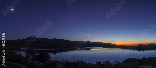 Panorama of colorful twilight with Crescent moon and planets Venus, Saturn, Jupiter over mountain lake, Vale do Rossim, Serra da Estrela, Portugal
