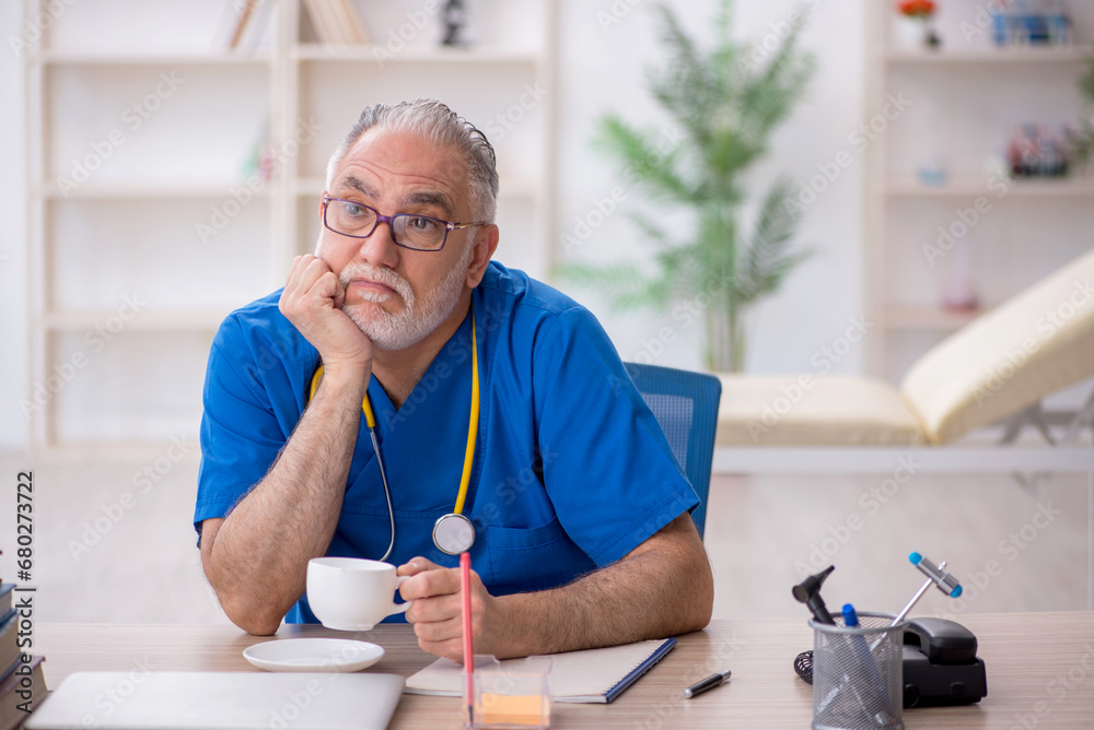 Old male doctor drinking coffee during break Old male doctor drinking coffee during break