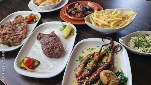 Variety of Portuguese traditional food meat dishes veal pork and octopus with lemon tomato fries, oilive oil rice. Closeup photo