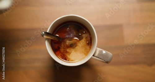 Pouring Milk Into Mug of Tea and Stirring With a Spoon photo