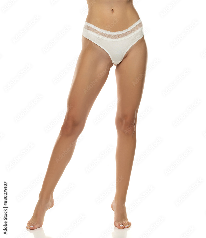 woman's legs are elegantly posed, showcasing white panties from the front on white background. woman's legs are elegantly posed, showcasing white panties from the front on white background.