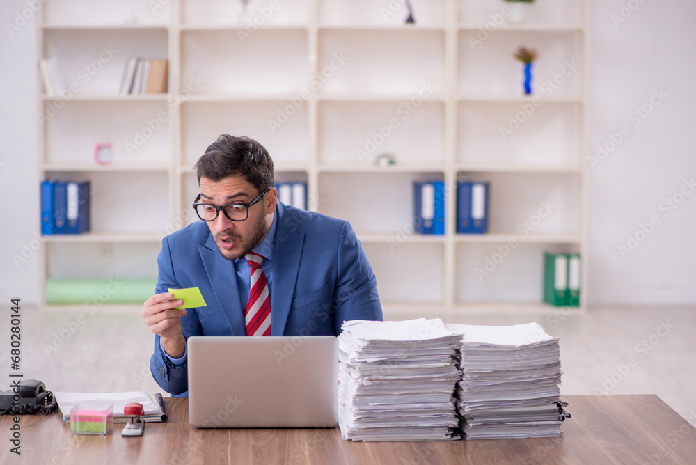 Young male employee unhappy with excessive work in the office Young male employee unhappy with excessive work in the office