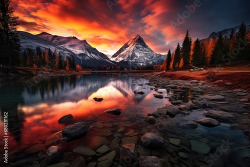  a beautiful sunset over a mountain lake with rocks in the foreground and a mountain range in the back ground.