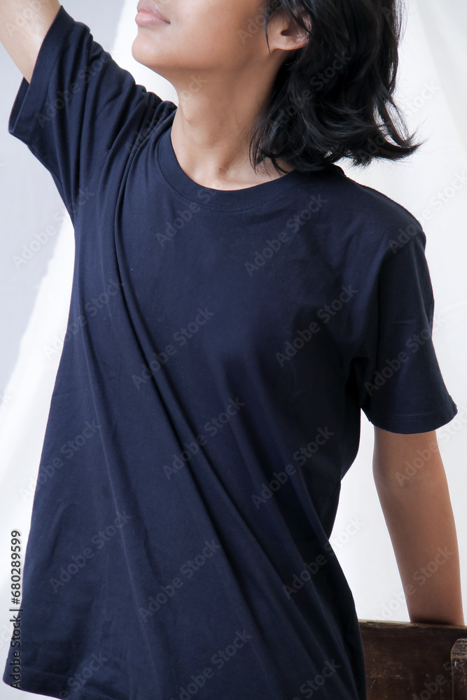 Fototapeta premium Clothing model. Young Asian man with long curly hair close up shot isolated on white. Asian young man wearing navy blue t-shirt isolated on white background. As if he were modeling a plain t-shirt.