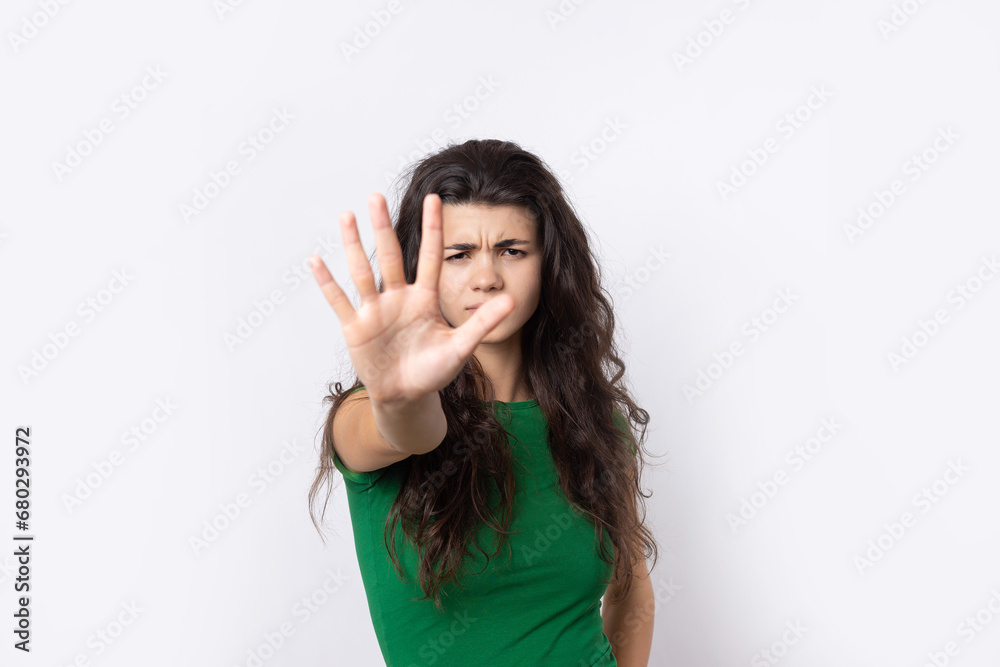 Portrait of a serious young woman showing stop gesture with her palm over white background Portrait of a serious young woman showing stop gesture with her palm over white background