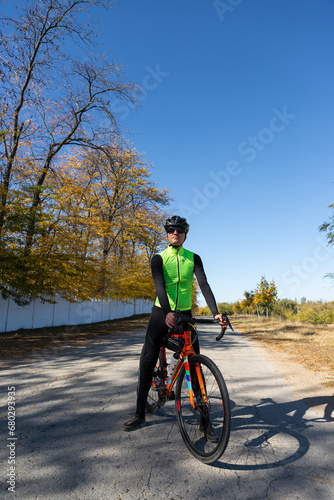 A man in clothes stands with a bicycle on an autumn sunny day. Cyclist in the park.