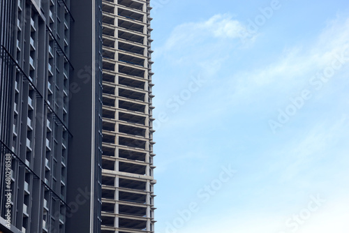 high rise building with concrete frame, building under construction facing bright blue sky. multi-storey residential building, stylish building, modern architectural style. Banner, space for text.