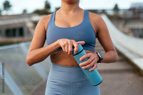 Active woman with smartwatch and water bottle outdoors photo