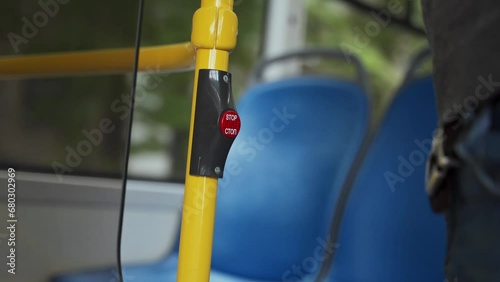 Close up shot of red stop button on handrail pushed by man in moving bus. Man presses pushbutton to make sign for driver to get off public transport photo