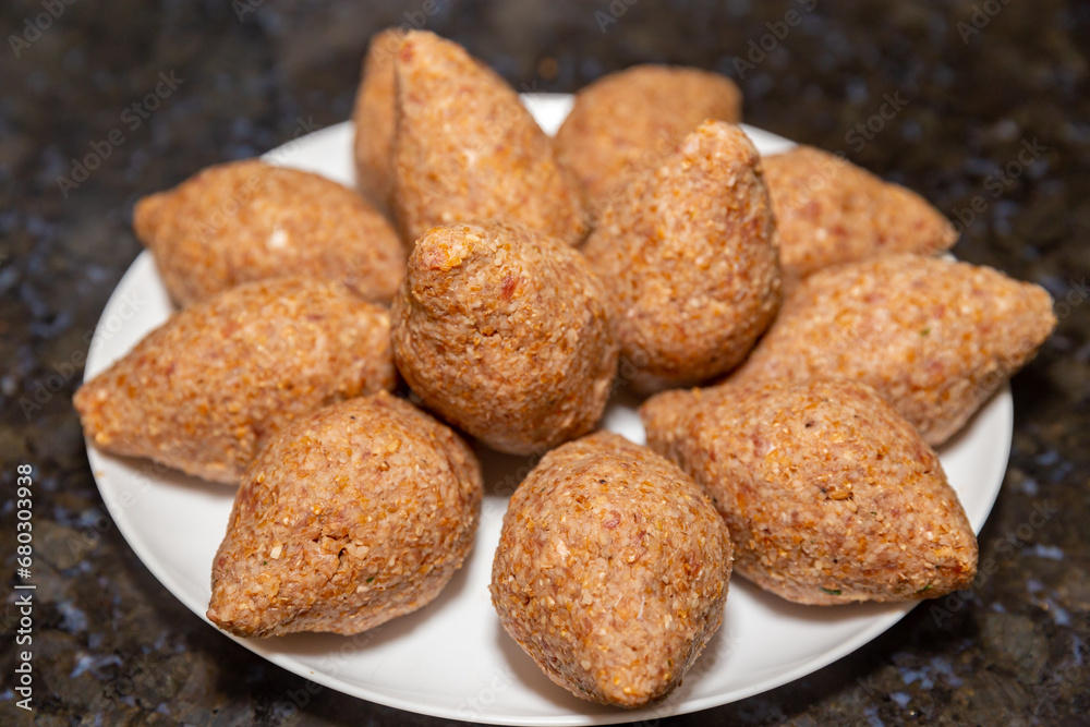 Traditional meat kibbeh (kibe), typical food from the middle east, typical turkish, syrian or arabic food, savory from arabic cuisine on white background with selective focus (kibe) Traditional meat kibbeh (kibe), typical food from the middle east, typical turkish, syrian or arabic food, savory from arabic cuisine on white background with selective focus (kibe)