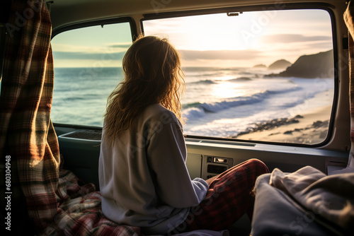 Generative AI illustration of anonymous blonde woman sitting inside a van while looking out at the ocean and the sunset from the rear window photo