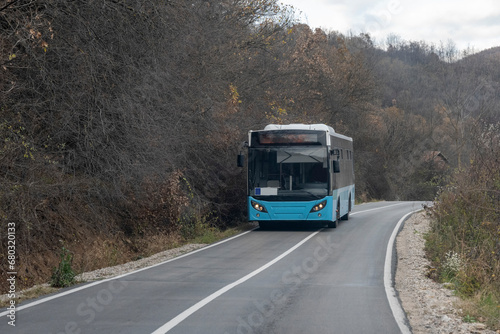 The blue intercity bus goes along the rural highway.