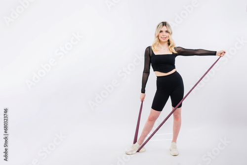 Young woman workout with resistance band on white background. Strength and motivation.