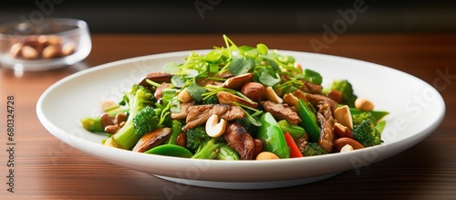 The plate was filled with a healthy lunch dish, consisting of a colorful salad made with an array of green vegetables, mushrooms, and beans stir-fried with spicy pork, topped with a handful of peanuts