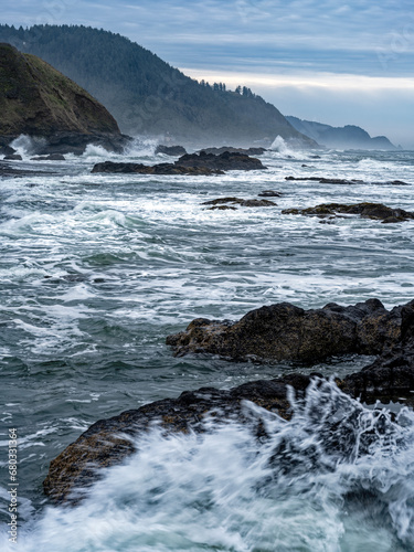 Waves splash against the basalt slabs along the shore of the Pacific Ocean near Florence, Oregon, USA