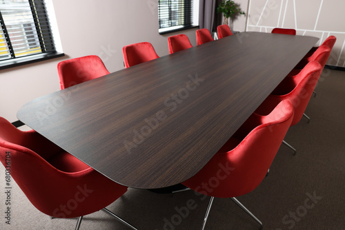 Empty conference room with stylish red office chairs and large wooden table photo
